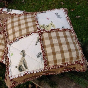 May include: A square rag quilt pillow featuring a patchwork design of white fabric with printed poodle and dog illustrations alternating with tan and white gingham check squares. The edges are finished with frayed, ruffled seams in dark red.