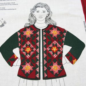 May include: A fabric panel featuring a woman's figure wearing a quilted jacket. The jacket is primarily red with green sleeves and accents, and a star pattern. The background is white with sewing diagrams and text.