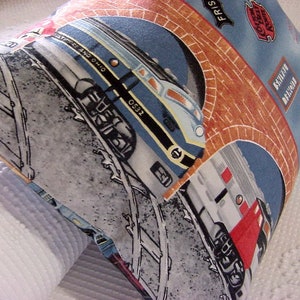May include: Square pillow with a train design. The pillow features a blue background with illustrations of trains, brick archways, and railroad tracks. The text "Baltimore and Ohio" is visible on the pillow.