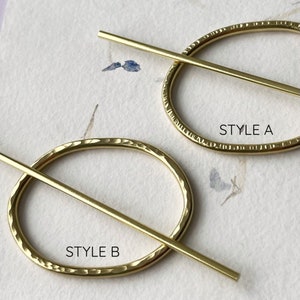 May include: Two gold-toned metal hair clips with a hammered finish. The top clip is labeled "STYLE A" and the bottom clip is labeled "STYLE B".