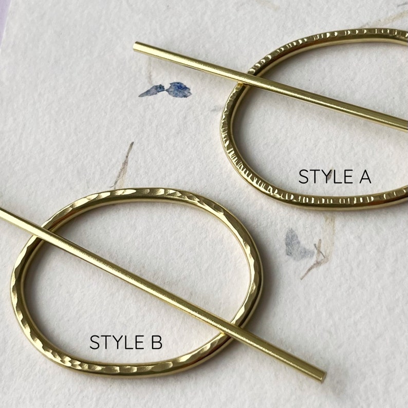 May include: Two gold-toned metal hair clips with a hammered finish. The top clip is labeled "STYLE A" and the bottom clip is labeled "STYLE B".