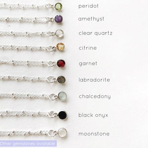 May include: A display of ten silver chains with different gemstone pendants. The gemstones are peridot, amethyst, clear quartz, citrine, garnet, labradorite, chalcedony, black onyx, and moonstone. The text "Other gemstones available" is at the bottom of the image.