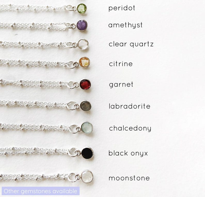 May include: A display of ten silver chains with different gemstone pendants. The gemstones are peridot, amethyst, clear quartz, citrine, garnet, labradorite, chalcedony, black onyx, and moonstone. The text "Other gemstones available" is at the bottom of the image.