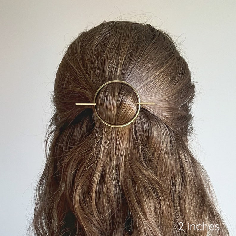 May include: Gold hair clip with a circle design. The clip is 2 inches long.