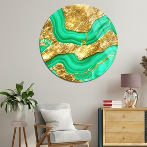 Könnte beinhalten: Runde Wandkunst mit einem Gold- und Grünmalachit-Design. Das Kunstwerk zeigt fließende grüne Adern vor einem goldenen Hintergrund. Das Stück wird an einer Wand in einem Raum mit Stuhl, Schrank und Pflanzen ausgestellt.