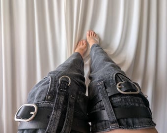 Straight leg, over the knee upcycled black denim leg warmers with leather belts and metallic hardware