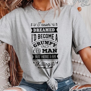 May include: A gray t-shirt with a black graphic that reads "I never dreamed I'd become a grumpy old man but here I am killing it!"
