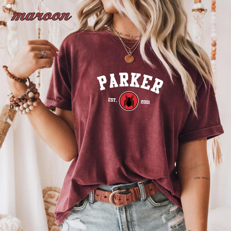 May include: A maroon t-shirt with white text that reads "Parker Est. 2001" and a red circle with a black spider inside.