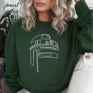 Pu&ograve; includere: Felpa verde bosco con un contorno bianco di una testa di robot.