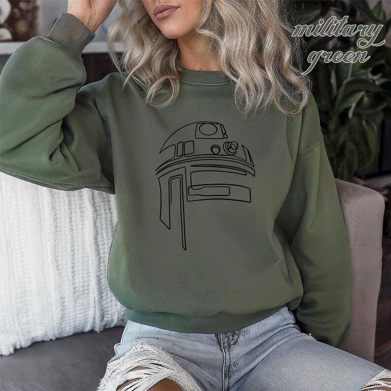 Pu&ograve; includere: Una felpa verde militare con un contorno nero di una testa di robot sul davanti.