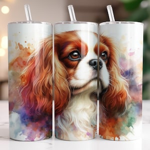 Op de afbeelding: Drie roestvrijstalen bekers met een aquarel schilderij van een Cavalier King Charles Spaniel. De hond heeft bruin en wit haar, met een zachte blik. De achtergrond heeft kleurrijke aquarel spetters.