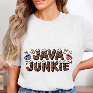 May include: White t-shirt with the words "JAVA JUNKIE" in a playful, coffee-themed design. The letters are filled with coffee beans and topped with whipped cream. Small coffee cups in blue and red are on either side.