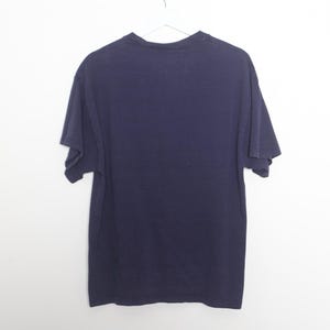 May include: A dark blue t-shirt with short sleeves.