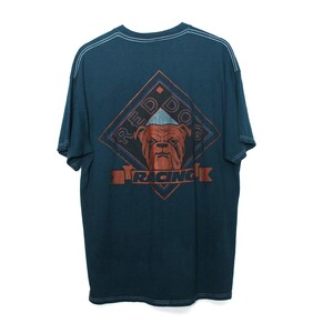 May include: Dark teal t-shirt with a graphic of a bulldog's face inside a diamond shape. The diamond is outlined in red and blue, with the words "RED DOG RACING" in a banner below the dog.
