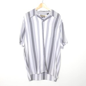 May include: A short-sleeved button-down shirt with vertical stripes in shades of gray and white. The shirt is hanging on a wooden hanger against a white background. The shirt has a chest pocket and a collar.