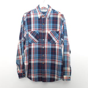 May include: A long-sleeved plaid shirt in shades of blue, red, and white, hanging on a white hanger. The shirt has two chest pockets and a button-down front. The plaid pattern is a classic design.