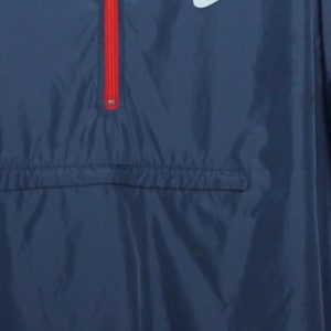 May include: Navy blue windbreaker jacket with a red zipper and a white logo. The jacket has a front pocket and a drawstring at the bottom. The jacket is made of a lightweight material.
