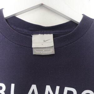 May include: A navy blue t-shirt with a white logo that says "Orlando" and a Nike logo. The tag says "L" and "Made in Honduras".