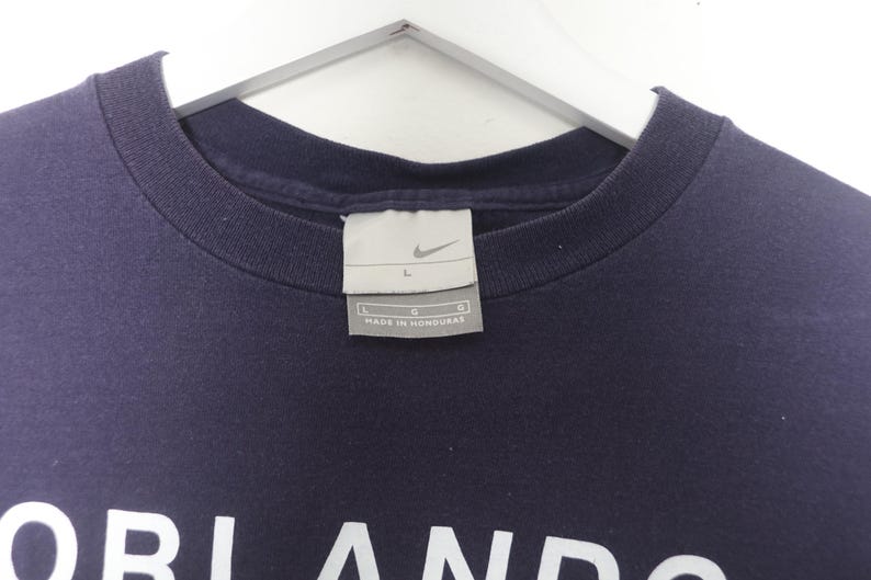 May include: A navy blue t-shirt with a white logo that says "Orlando" and a Nike logo. The tag says "L" and "Made in Honduras".