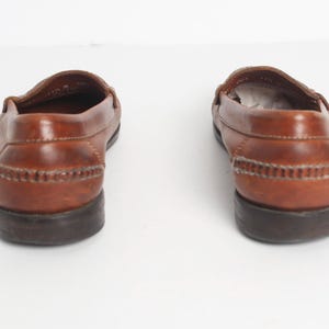 May include: A pair of brown leather loafers with a stitched detail around the top of the shoe. The shoes have a dark brown sole.