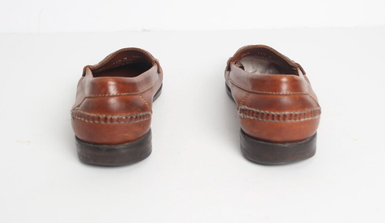 May include: A pair of brown leather loafers with a stitched detail around the top of the shoe. The shoes have a dark brown sole.