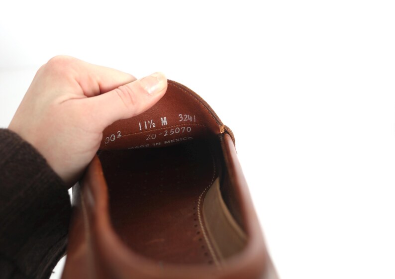 May include: Close-up of the inside of a brown leather shoe with the size 11 1/2 M, 20-25070, 3241, and Made in Mexico printed on the insole.