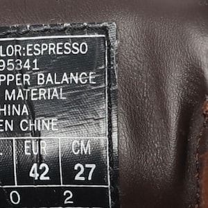 May include: A brown leather shoe with a size tag that reads "SN 7496 COLOR:ESPRESSO PATENT D395341 LEATHER UPPER BALANCE MAN MADE MATERIAL MADE IN CHINA FABRIQUE EN CHINE U.S. 9 U.K. 8 EUR 42 CM 27".