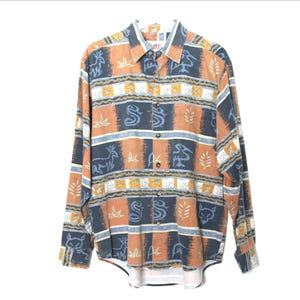 May include: A long-sleeve button-down shirt featuring a multi-colored pattern of orange, dark blue, and white. The design includes horizontal bands with repeating animal silhouettes, leaf motifs, and geometric shapes across the fabric.