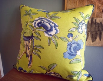 May include: A green throw pillow with a blue and white floral pattern and a green bird design.