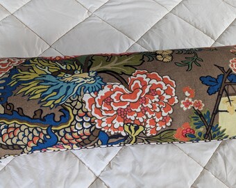 May include: Rectangular decorative pillow with a brown background and a colorful dragon and floral pattern. The dragon is blue, yellow, and green, and the flowers are orange and red.