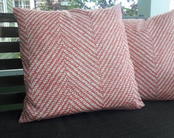 May include: Two red and white patterned throw pillows with a chevron design. The pillows are on a dark gray surface.