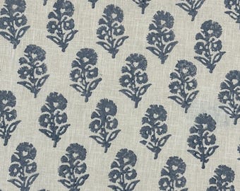 May include: A fabric with a repeating pattern of blue floral motifs on a light beige background. The flowers are stylized with detailed petals and leaves, creating a textured appearance. The design is evenly spaced across the fabric.