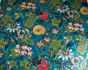 May include: Teal fabric with a floral pattern featuring pink, white, yellow, and red flowers. The flowers are surrounded by green leaves.
