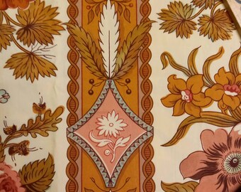 May include: A white fabric with a repeating pattern of orange, pink, and brown floral designs. The fabric has a vertical stripe of orange, pink, and brown geometric shapes.