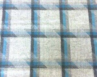 May include: A close-up of a fabric with a plaid pattern. The fabric has a gray background with a grid of black lines and teal blue accents. The pattern is a classic plaid design.