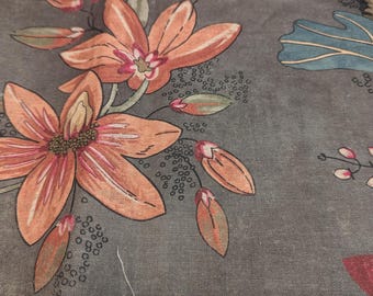 May include: A gray fabric featuring a botanical print with large orange flowers, small closed buds, and blue leaf accents. The design includes delicate black dotted patterns and thin stems, creating a detailed floral motif across the textile surface.