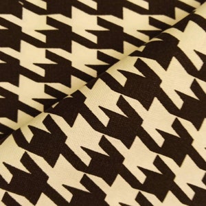 May include: A close-up of a fabric with a houndstooth pattern. The fabric is white with black houndstooth shapes.
