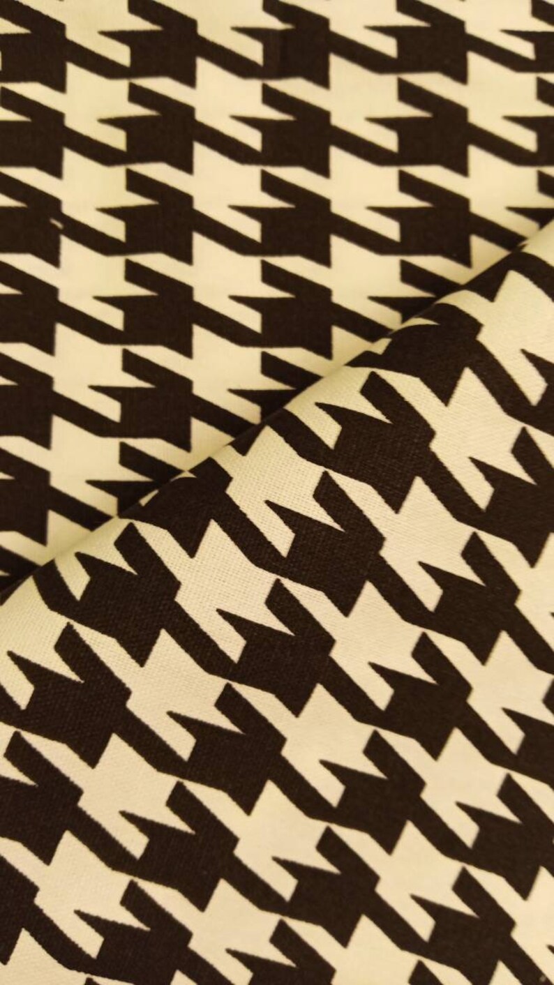 May include: A close-up of a fabric with a houndstooth pattern. The fabric is white with black houndstooth shapes.