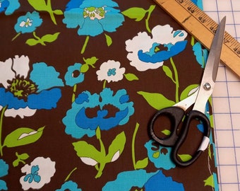 May include: Brown fabric with a blue and white floral pattern. A pair of scissors and a wooden ruler are on top of the fabric.