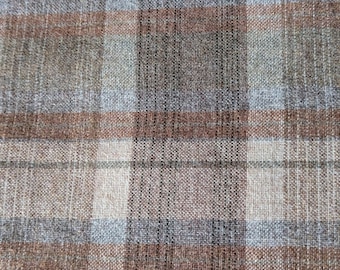 May include: Close-up of a woven fabric with a plaid pattern. The design features a grid of intersecting lines in shades of brown, gray, and blue. The fabric has a textured appearance, suggesting a natural fiber like wool or linen.