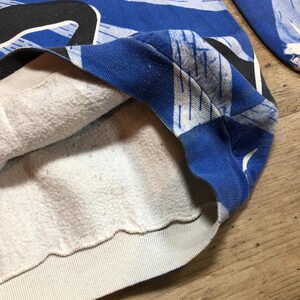 May include: A blue and white patterned sweatshirt with a white fleece lining. The sweatshirt has a ribbed hem and cuffs.