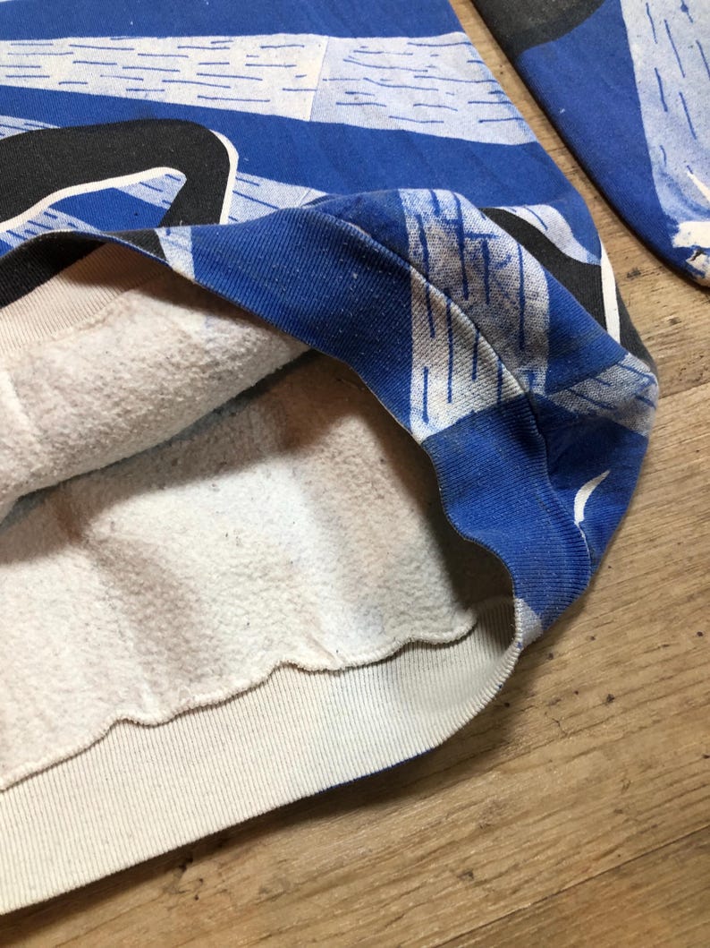 May include: A blue and white patterned sweatshirt with a white fleece lining. The sweatshirt has a ribbed hem and cuffs.