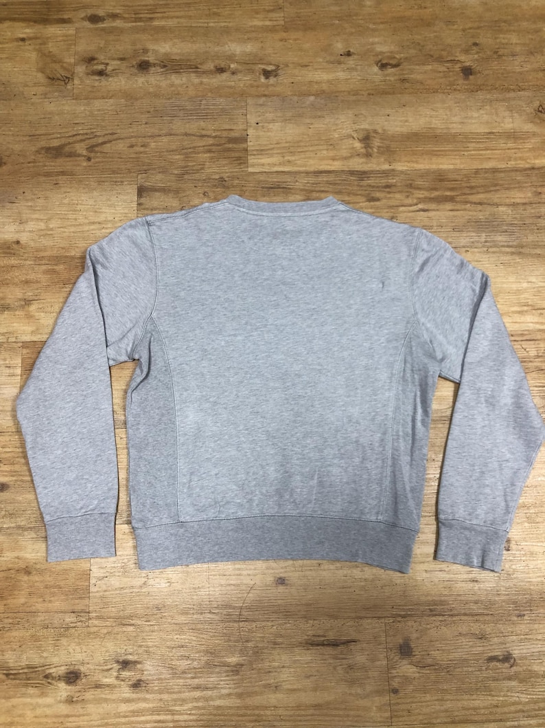 Puede incluir: Una sudadera gris de manga larga con cuello redondo.