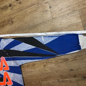 May include: A blue, black, and white long-sleeved shirt with a geometric pattern and the word "FILA" printed in red on the front.