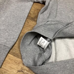 Puede incluir: Una sudadera gris con una etiqueta blanca que dice "ART. N. 7101 TC. M. COTTON 100%"