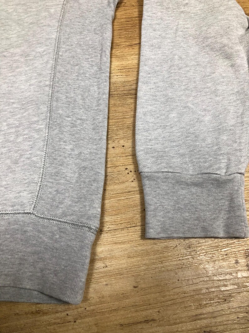 Puede incluir: Una sudadera gris con mangas largas y pu&ntilde;os de canal&eacute;. La sudadera est&aacute; hecha de una tela suave y c&oacute;moda.