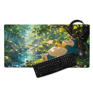 Puede incluir: Una alfombrilla de escritorio rectangular con una ilustración impresa de un Snorlax azul y dos Pikachu amarillos durmiendo bajo un árbol junto a un arroyo en el bosque. Un teclado negro, un ratón negro y auriculares negros están colocados encima.