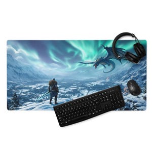 May include: A large rectangular mouse pad featuring a fantasy landscape with a warrior, dragon, and aurora borealis. A black keyboard, mouse, and headphones are on the pad. The pad is designed for gaming and computer use.