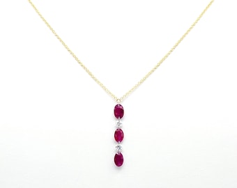 Op de afbeelding: Een gouden ketting met een hanger met vier ovale rode robijnen en kleine heldere diamanten.