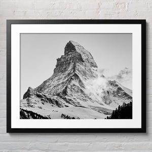 May include: A black and white photograph of the Matterhorn mountain in Switzerland. The mountain is covered in snow and ice, and the sky is cloudy.